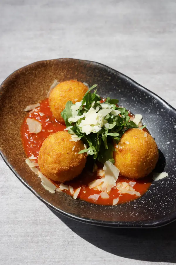 Arancini balls on napolitana sauce with rocket and parmesan