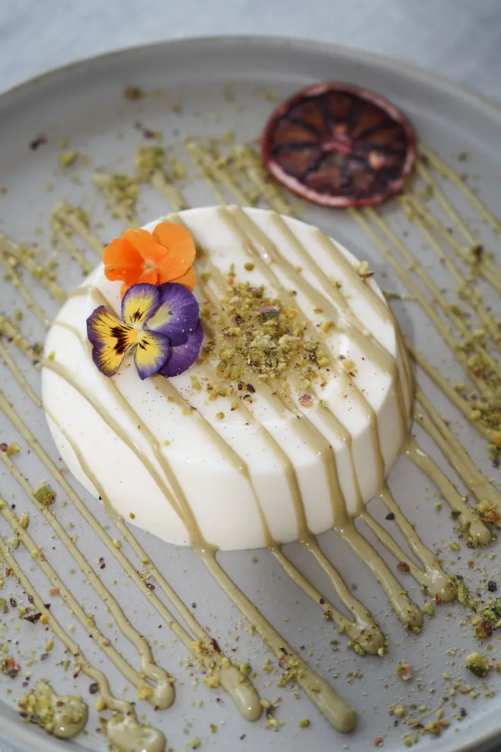 A white dessert with berry sauce